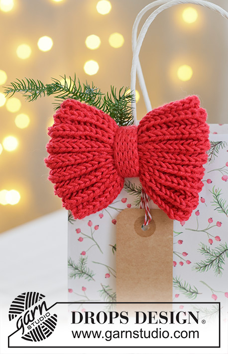 Holly Red Bow / DROPS Extra 0-1628 - Prjónuð slaufa / jólaskraut úr DROPS Cotton Merino. Stykkið er prjónað frá hlið að hlið í klukkuprjóni með i-cord og tvöföldu prjóni. Þema: Jól.