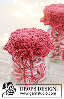 Holiday Jar Keeper / DROPS Extra 0-1629 - Crocheted jam jar cover in DROPS Belle. The piece is worked in the round, middle outwards, with puff-stitches and fan pattern. Theme: Christmas.