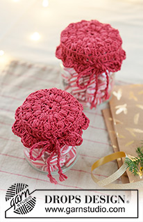 Holiday Jar Keeper / DROPS Extra 0-1629 - Crocheted jam jar cover in DROPS Belle. The piece is worked in the round, middle outwards, with puff-stitches and fan pattern. Theme: Christmas.