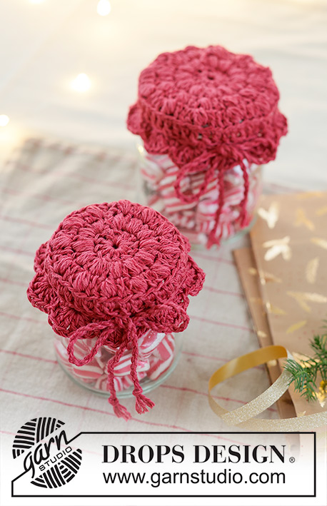 Holiday Jar Keeper / DROPS Extra 0-1629 - Crocheted jam jar cover in DROPS Belle. The piece is worked in the round, middle outwards, with puff-stitches and fan pattern. Theme: Christmas.