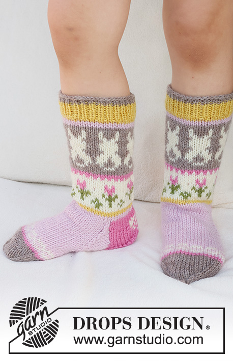 Dancing Bunny Socks / DROPS Children 41-35 - Stickade sockor till barn i DROPS Karisma. Arbetet stickas uppifrån och ner, i slätstickning med flerfärgat mönster med hare / påskhare, blomma och hjärta.
Storlek 24 - 43. Tema: Påsk.
