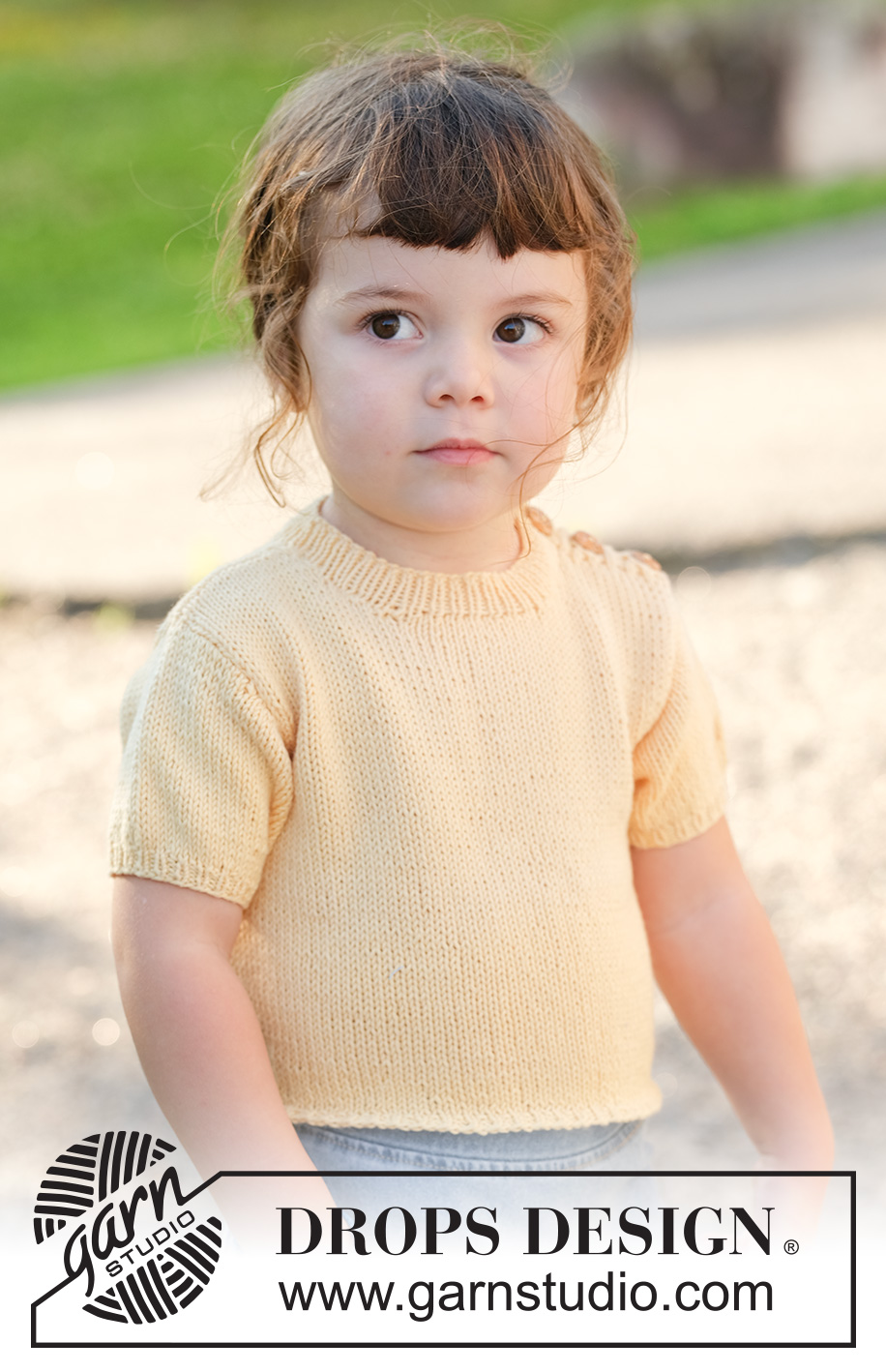 Sunshine Sprout / DROPS Children 49-3 - Jersey de punto para niños en DROPS Cotton Merino. La pieza está tejida de abajo hacia arriba con mangas cortas y borde para botones sobre el hombro. Tallas 2 – 12 años.