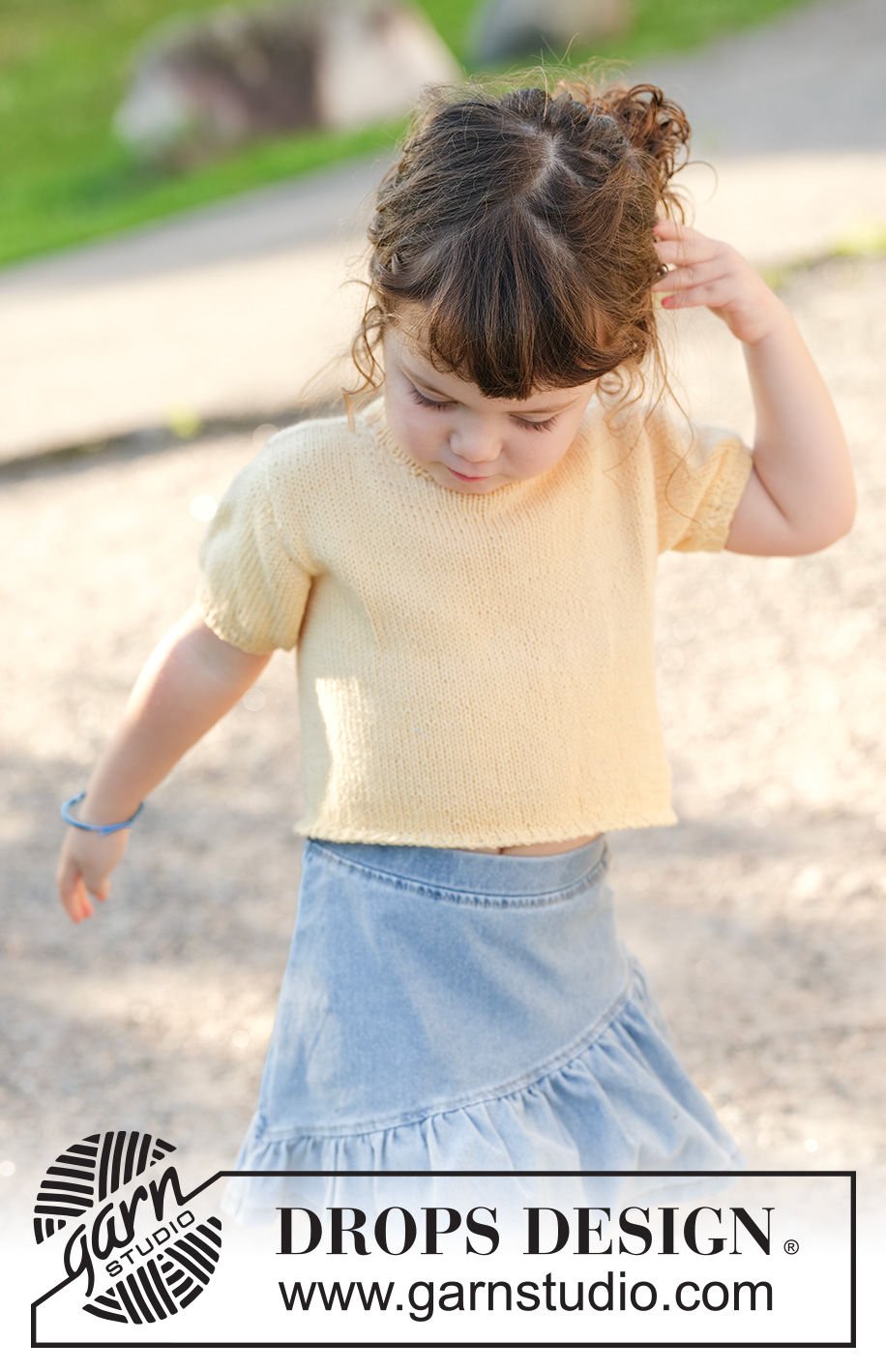 Sunshine Sprout / DROPS Children 49-3 - Jersey de punto para niños en DROPS Cotton Merino. La pieza está tejida de abajo hacia arriba con mangas cortas y borde para botones sobre el hombro. Tallas 2 – 12 años.